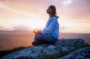 mujer sentada meditando al atardecer